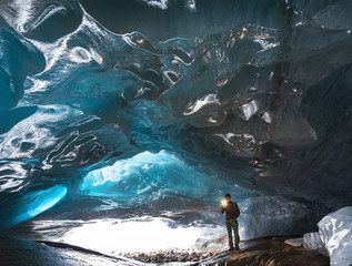 man under the thickness of ice inside the grotto of the Alibek glacier in Dombay, Caucasus
