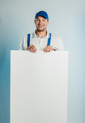 Mockup image of a young high smiling worker holding empty white banner. White or blue background. Bussines concept.