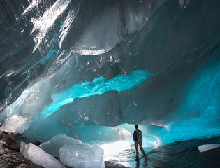 human stands inside the glacier cave of the Alibek mountain glacier in Dombay