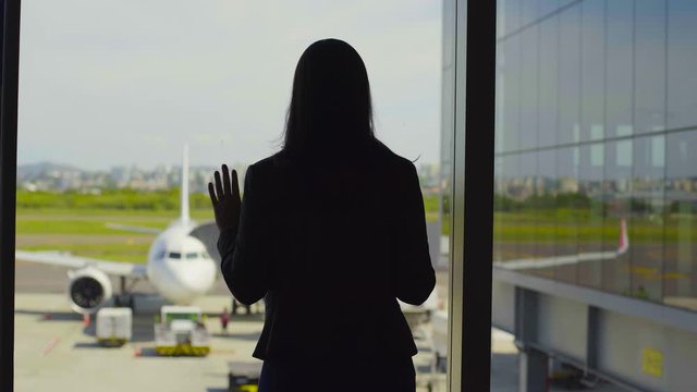Pensive woman stay against terminal window of International airport. Business lady 