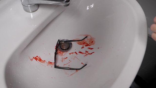 Slow motion drop of nerdy spectacles with blood smeared, closeup 