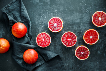 Flat lay food composition with blood oranges on a dark blue background.