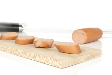 Group of four slices one piece of pork frankfurt sausage on wooden cutting board with steel knife isolated on white background