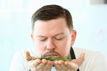 Blogger Beard Chef Smelling Aromatic Rosemary Herb. Man Holding Green Herbal Plant on Hands. Cook with Greens Ingredient for Vegetarian Food. Natural Culinary Spice Blog Head and Shoulders Photography