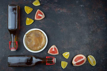 Kombucha superfood pro biotic tea fungus beverage in glass bottle with orange, grapefruit on dark background.