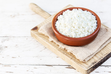 Homemade cottage cheese in a ceramic bowl on white old wooden table. Healthy food. Fresh dairy products. Top view