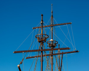 Sailing masts of an antique ship on blue sky background