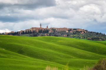 Fototapeta na wymiar Amazing spring landscape with green rolling hills and old town of Pienza in the distance, Tuscany, Italy