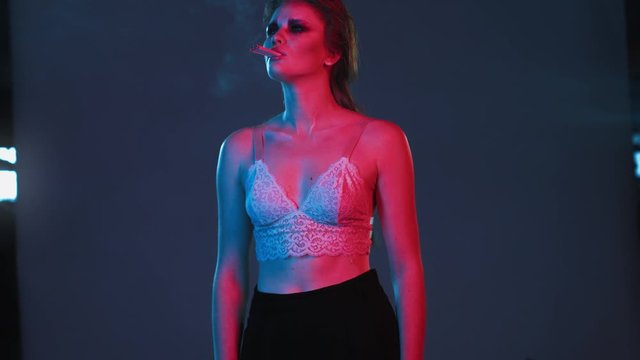 young red haired sexy woman smokes three cigarettes at time, red and blue neon lighting, young redhaired girl in underwear or lingerie with fashion makeup and hairstyle