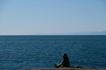 Ragazza sola in riva al mare ammira le onde del mare mentre il vento le scompiglia i capelli
