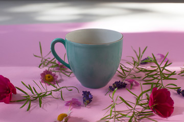 cup of coffee/tea with flowers on pink background 