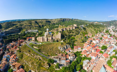 Fototapeta premium Panorama of the old town on Sololaki hill, crowned with Narikala fortress, the Kura river and cars traffic with blure in Tbilisi, Georgia.