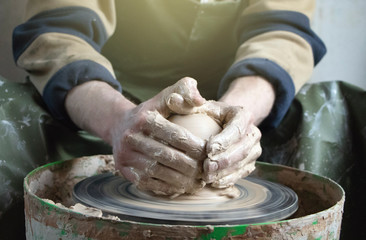 Hands of a potter on a pottery wheel close-up. Old traditional art, handmade, clay and ceramic...
