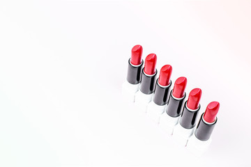 Six open rods of red lipstick are placed on a light background. Colorful decorative cosmetics.
