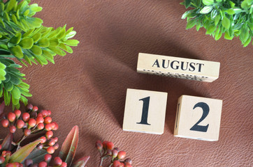 August 12, Number cube design with flower on brown lether background.