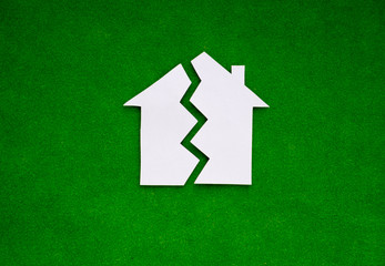 two halves of the house made of white paper on a green background. the concept of property, the...