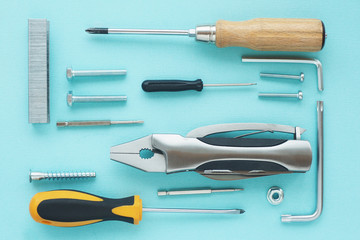 .Pattern of tools: nippers, screwdrivers, keys, bolts, staples for a stapler, self-tapping screws, nut on a blue background..