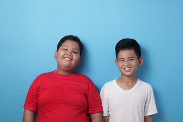 Fototapeta premium Two Asian boys looking at camera, smiling and laughing, best friends happiness