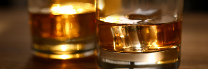 Focus on glasses of whisky or bourbon with ice-cubes. Glassful of delicious beverages on wooden...