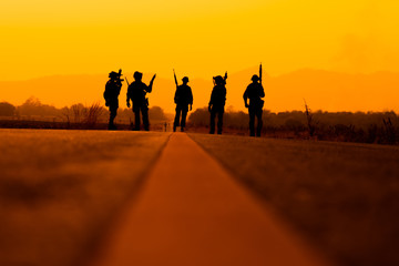 silhouette of Soldier team backdrop of sunset sky.Soldier with machine gun patrolling 