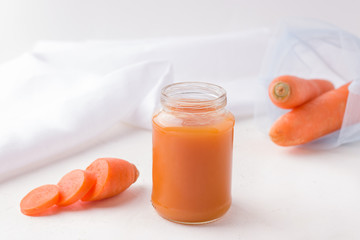 Homemade carrot baby food next to fresh ingredients. sure copy space