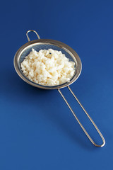Kefir grains in a sieve on a blue background
