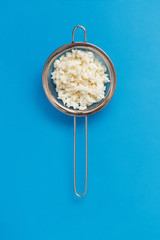 Kefir grains in a sieve on a blue background