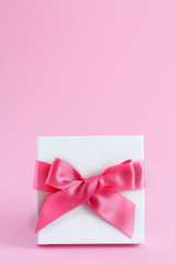 White gift box with a bow on a light pink background