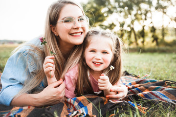 Blonde mother with two cute daughters are walking and having fun outdoors. Stylish, casual clothes.