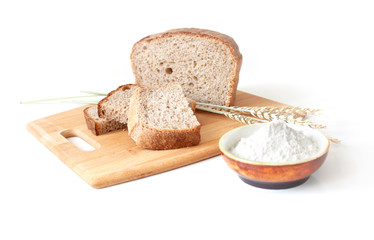 Rye and wheat bread. A loaf of bread on a cutting board with ears of wheat and a handful of wheat flour
