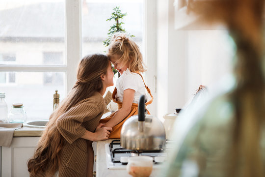 Two sisters play in a bright, stylish kitchen. Beautiful interior.