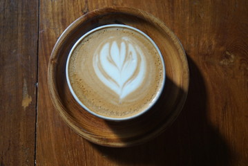 latte art on cappucino and coffee with the wooden saucer.