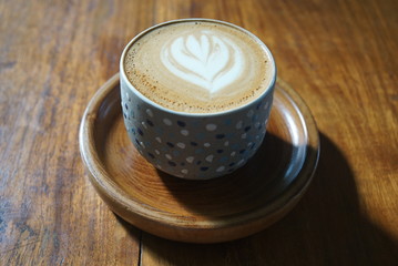 latte art on cappucino and coffee with the wooden saucer.