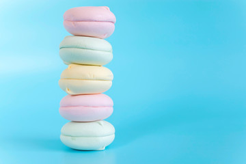 Fototapeta na wymiar Air marshmallows in pastel shades. A gentle marshmallows. A gentle zephyr on a blue background. Marshmallows in a light key.