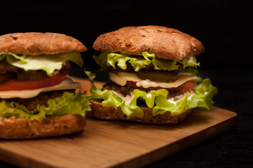 Russian burgers on a wooden Board with tomatoes on a dark background