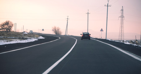 Fototapeta na wymiar Road traffic in the sunset. Car on asphalt under a cloudy sky.