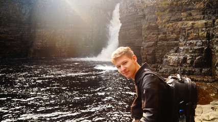 Young man in front of waterfall