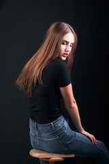 Look back portrait of a young girl with long hair and red lips against black background.