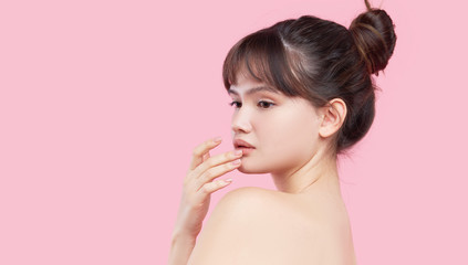 Obraz na płótnie Canvas Beautiful young asian korean woman with clean fresh skin touching her own face. Face treatment. Cosmetology, beauty and spa. Pink background