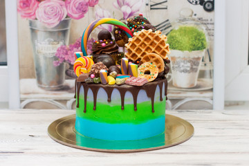 Blue and green cake with dark chocolate, cupcake, lollipops, cake pops, ferrero, waffle, candies and sprinkles.