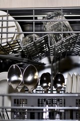 A large vertical fragment of the inner part of the dishwasher filled with clean dishes.