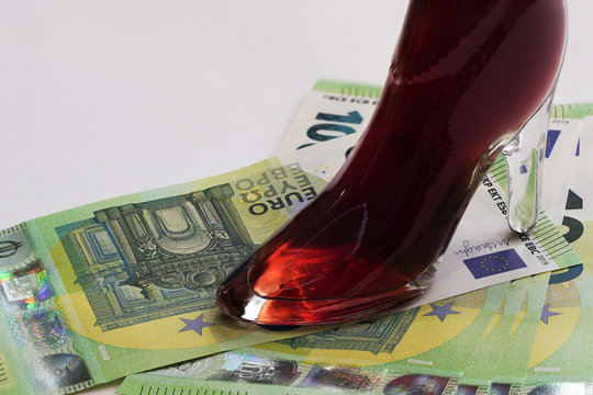 An elegant women's red crystal Shoe stands on paper Euro bills.