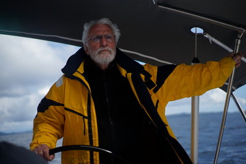 White bearded sailing senior, experienced skipper on a sailboat