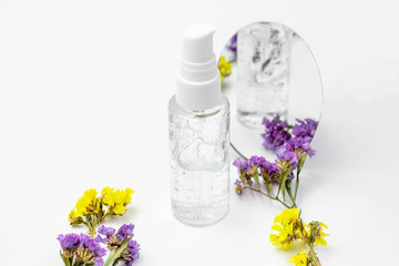 Cosmetic bottle with serum, gel, face cream on a white background with flowers. Skin cosmetics,...
