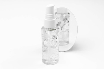 Cosmetic bottle with serum, gel, face cream on a white background with reflection in the mirror....
