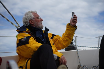 White bearded sailing senior, experienced skipper is checking the wind force, knots on a sailboat...