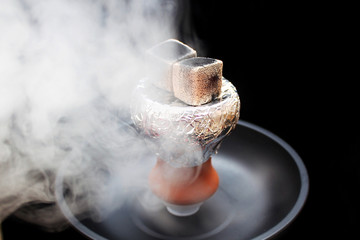Hookah bowl with foil and embers and a cloud of smoke nearby