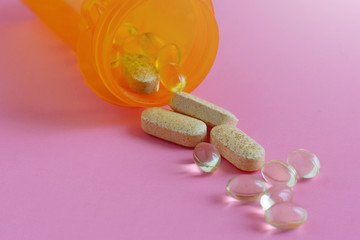 Drugs and  pills falling out of bottle on pink background.