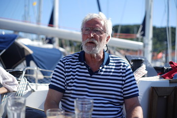 White bearded sailing senior, experienced skipper on a sailboat