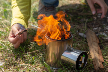 Tourist equipment and tools: camping stove burning out. Adding up logs.
